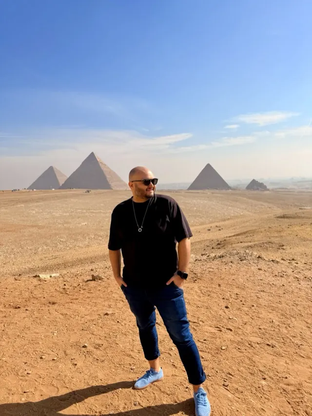 Hassan standing in the desert before the pyramids of Giza in Egypt