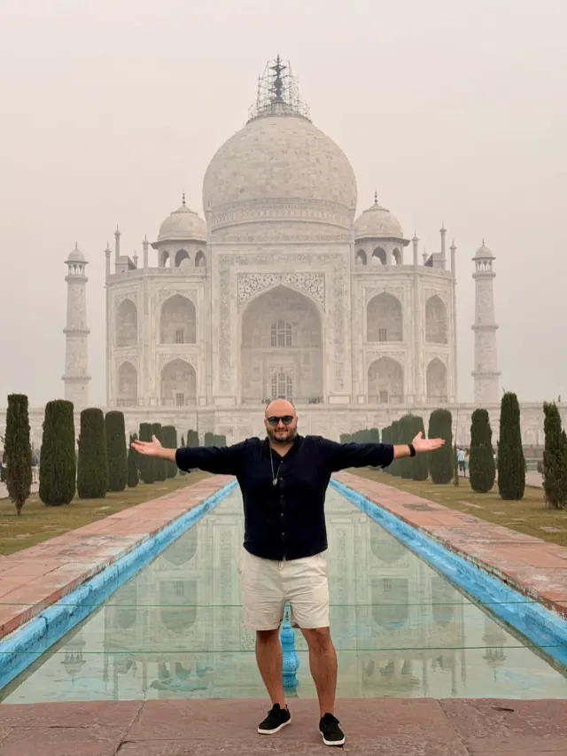 Hassan with arms spread wide in front of the Taj Mahal in India